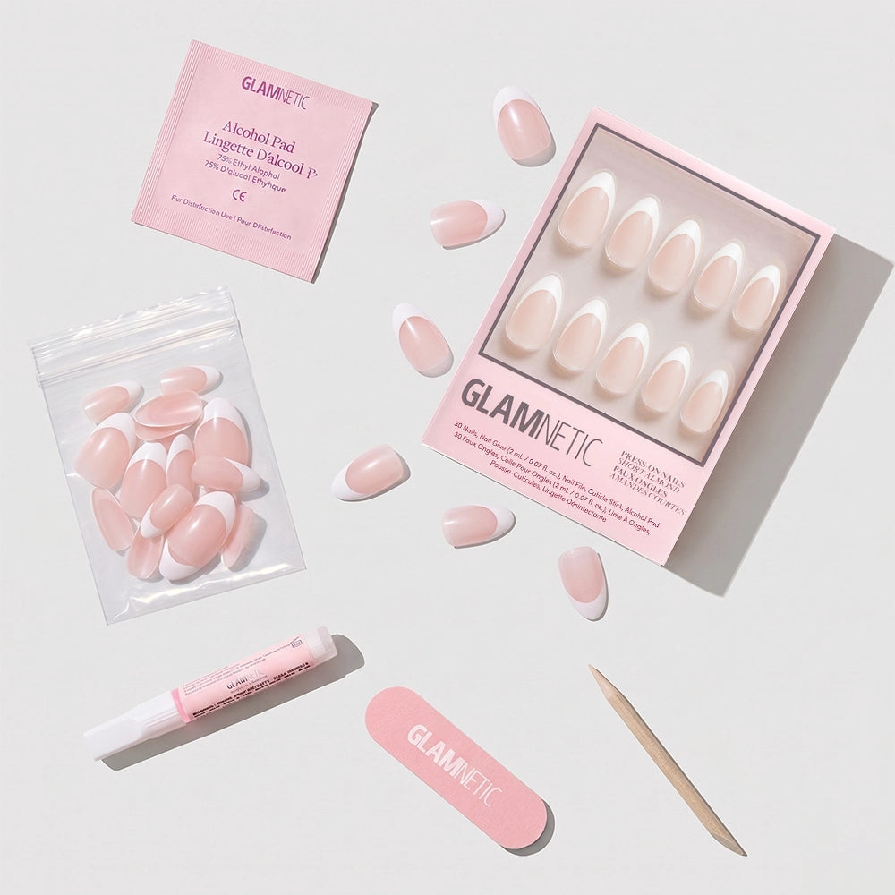 The Ma Damn almond-shaped pink and white press-on nails by glamnetic come with a nail file, glue, wooden cuticle stick, alcohol pad, and extra nails, all neatly arranged on a white surface. - Product image