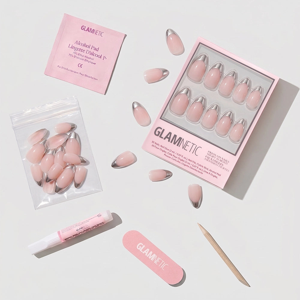 A flat lay of glamnetic's Mirror Mirror kit: vegan, cruelty-free short almond press-on nails in pink with chrome silver French tips, loose nails in a bag, nail glue tube, pink file, cuticle stick, and an alcohol pad. - Product image