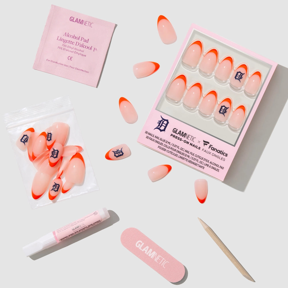 The glamnetic Detroit Tigers Press-On Nail Set features orange French tips, a nail glue pen, pink nail file, cuticle stick, alcohol pad, and extra nails—all displayed on a light gray surface. - Product image