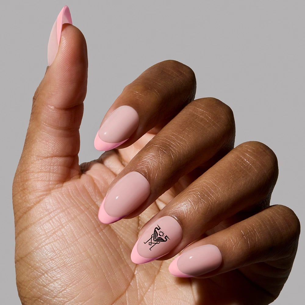 A hand with short almond nails painted in light and dark pink with minimalist black line art, featuring the Inter Miami CF Press-On Nail Set by glamnetic. The background is plain gray.