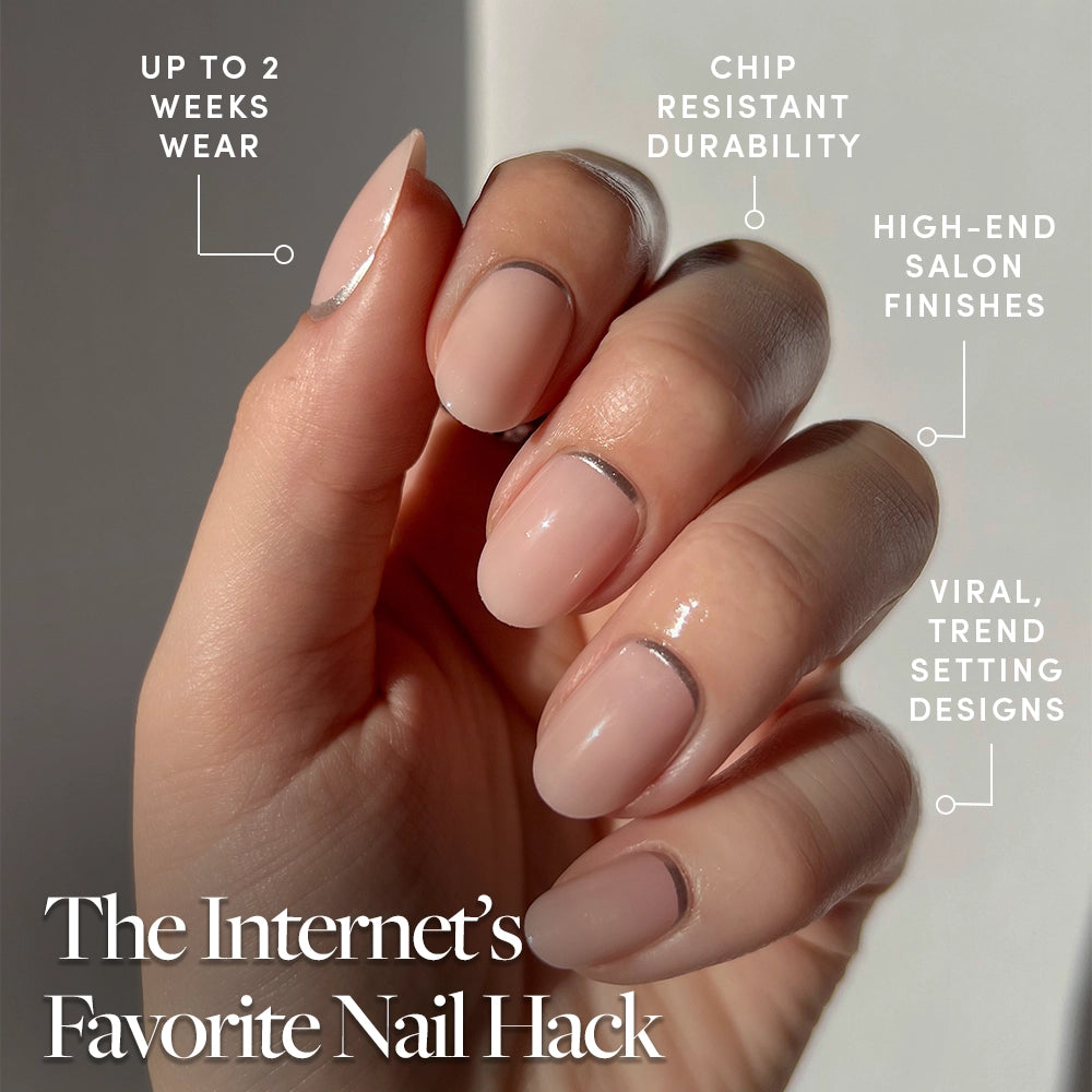 A hand shows "Silver Belle" by glamnetic: neatly manicured short round nails with a nude base and metallic silver tips. Enjoy up to 2 weeks wear, chip-resistant durability, salon-quality finish, and trendy viral designs. - Product image