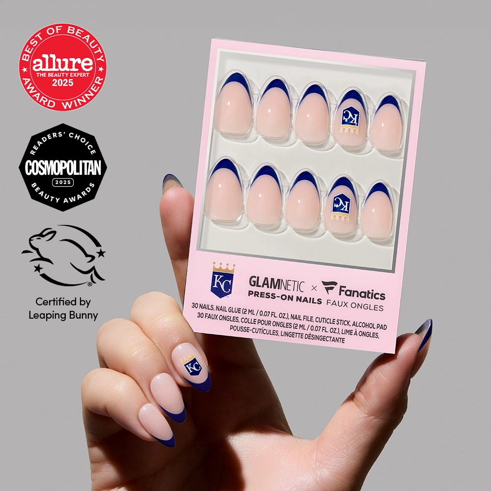 A hand holding a box of glamnetic MLB Press-On Nails with blue French tips and a KC logo, displayed in front of award and certification badges. - Product image