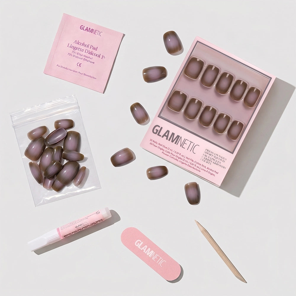 The glamnetic Eclipse set features short squoval press-on nails in a mauve taupe brown, shown with an alcohol pad, nail glue, nail file, wooden cuticle stick, and extra nails on a white background. - Product image