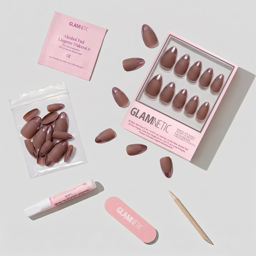 A flat lay of the glamnetic Terra press-on nail kit, featuring matte mauve almond nails, extra vegan nails in a bag, a pink nail file, wood stick, nail glue, and alcohol pad—all arranged on a light surface. - Product image