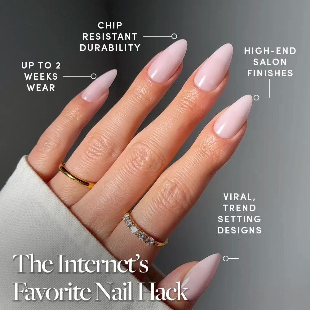A hand with long, almond-shaped, glossy pale pink nails is shown with gold rings. glamnetic’s Blush Blanket Press-On Nails deliver chip-resistant durability, up to 2 weeks of wear, salon-quality shine, and trending viral designs. - Product image