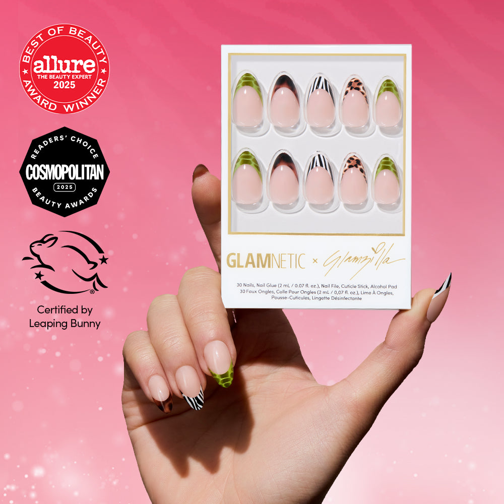 A hand with patterned, short almond nails holds a box of glamnetic 4 THE GLAMSQUAD press-on nails in pink, green, black, and animal print designs against a pink background with beauty award badges and a Leaping Bunny logo.