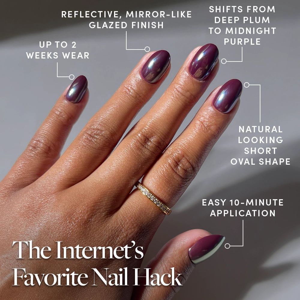 A hand is shown wearing glamnetic’s After Hours glossy press-on nails in a purple-glazed, mirror-finish oval shape. The nails feature subtle color shifts and a natural short oval design, offering up to 2 weeks of wear and easy 10-minute application. A gold ring adorns the ring finger. - Product image
