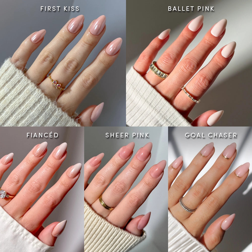 Five manicured hands display different nude and pink press-on nails from glamnetic's Au Naturel Almonds collection, featuring shades labeled: First Kiss, Ballet Pink, Fiancé, Sheer Pink, and Goal Chaser. Each hand is adorned with rings and some photos show a cozy sweater sleeve, highlighting how effortlessly salon-quality manis or nude ombré nails can be achieved—and styled—with your favorite accessories.