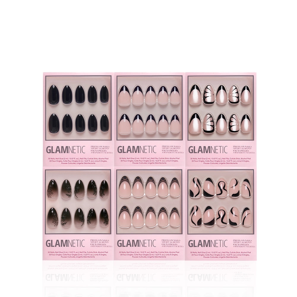 Six Glamnetic Back in Black Almonds press-on nail sets in pink boxes, each featuring different black and nude short almond designs—including solids, French tips, and abstract patterns—are arranged in two rows of three against a white background, offering a salon-quality manicure with striking black press-on nails. - Product image