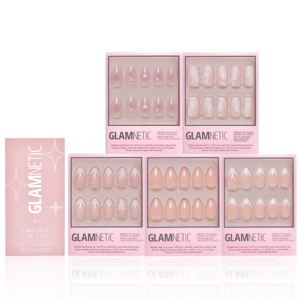 Six boxes of glamnetic Anns Sweethearts press-on nail sets, featuring nude and pink shades with short almond shapes, French tips, and delicate white designs, are arranged neatly against a white background. - Product image