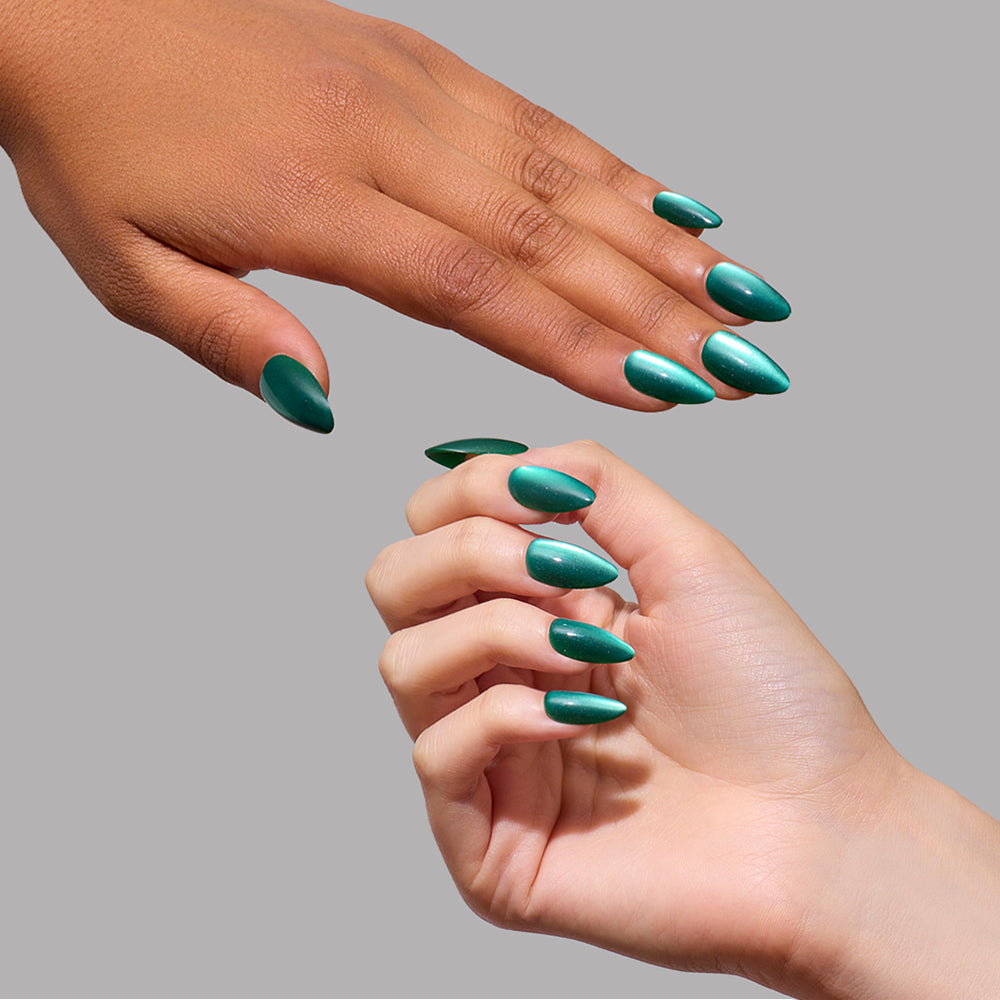 Arctic Aurora - Two hands showing short almond Arctic Aurora press-on nails by glamnetic with a shimmery, emerald green cat-eye finish.