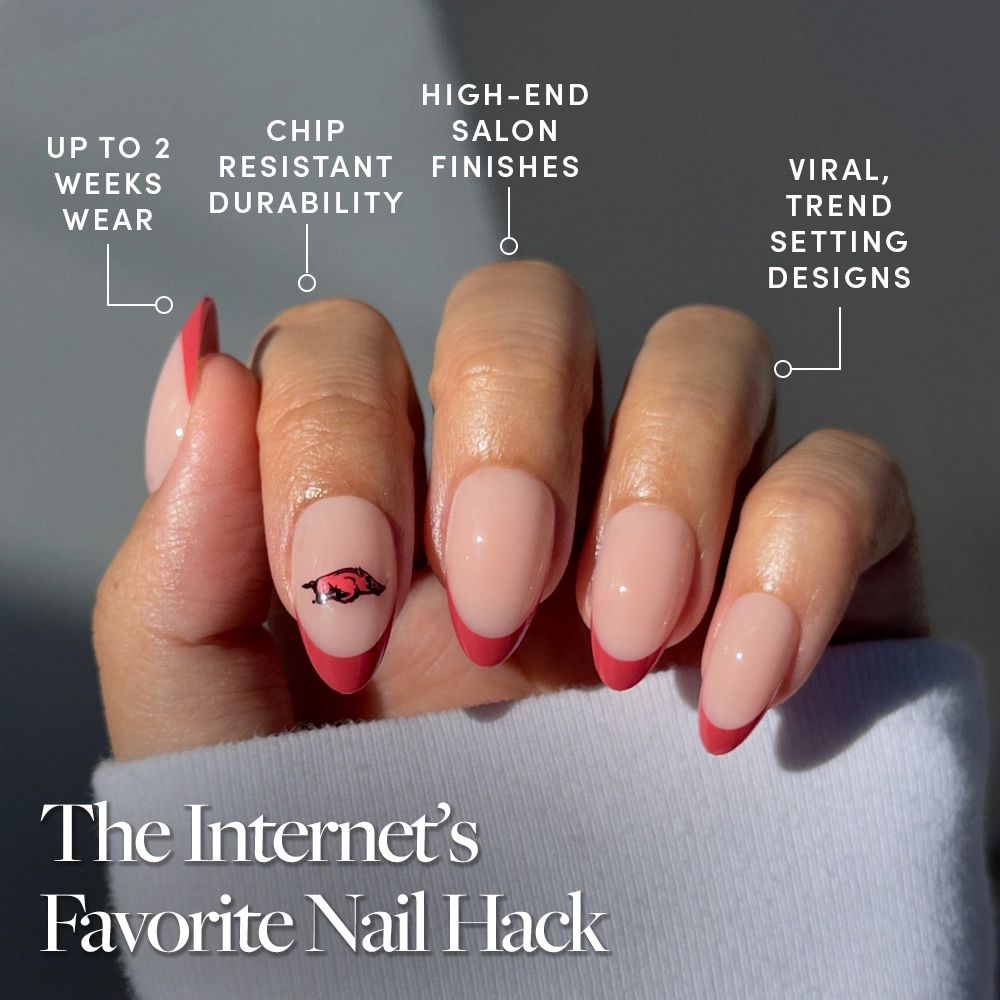 A hand with neatly manicured nails features the Arkansas Razorbacks Press-On Nail Set by glamnetic, showcasing pink tips and an eye design. Enjoy up to 2 weeks wear, chip resistance, salon finish & trendy styles—perfect for game day. The Internet’s Favorite Nail Hack. - Product image