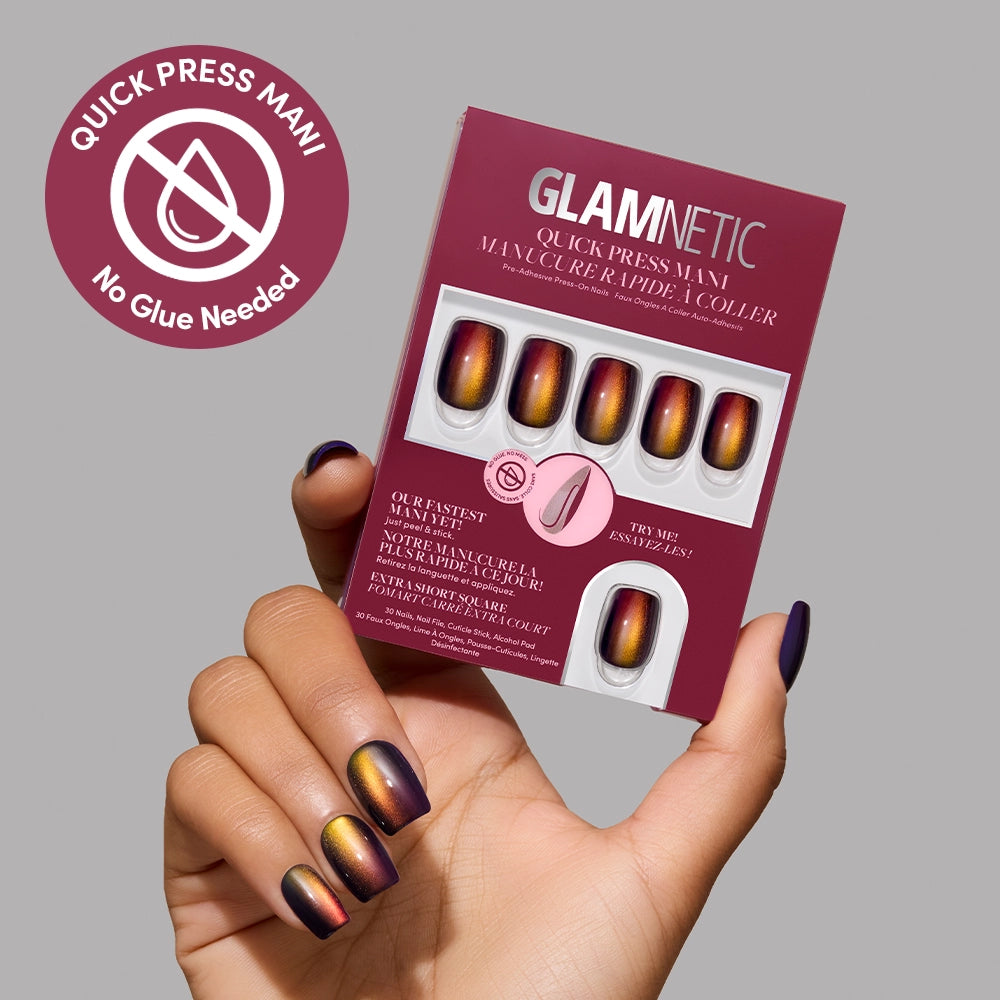 A hand with metallic ombré stick-on nails holds a box of glamnetic Aura Reading press-on nails. A “No Glue Needed” badge appears in the top left corner against a light gray background. - Product image