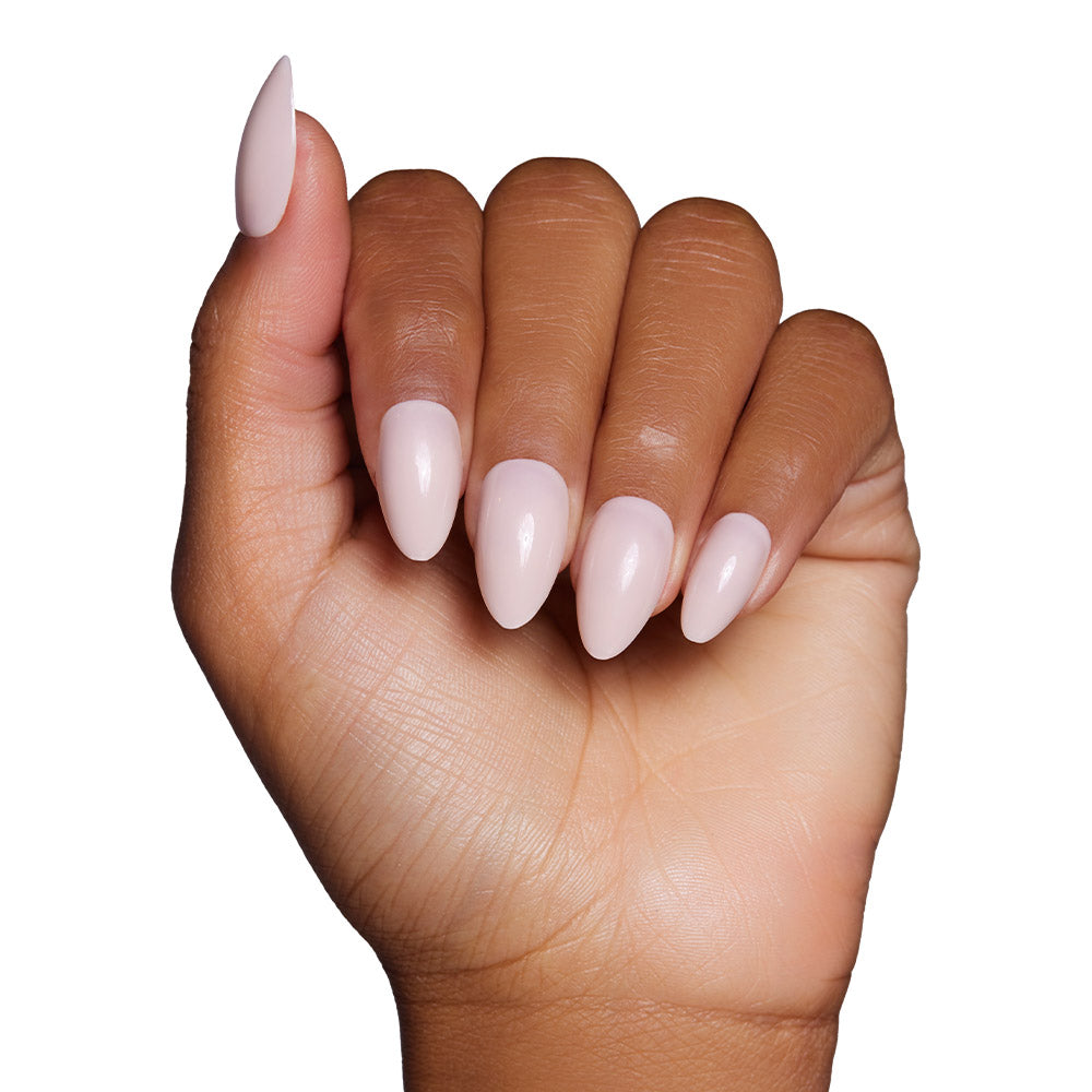A hand with medium brown skin displays the glamnetic Ballet Pink Nail Set in a short almond shape with a glossy finish against a white background. - Product image