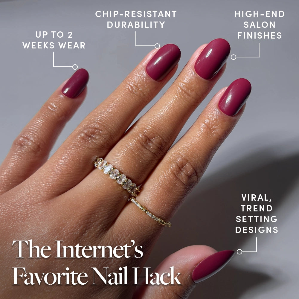A hand with glossy, dark pink Berry Maroon nails by glamnetic is shown wearing two gold rings. Text highlights benefits: up to 2 weeks’ wear, chip-resistant durability, high-end finishes, and trend-setting designs. - Product image