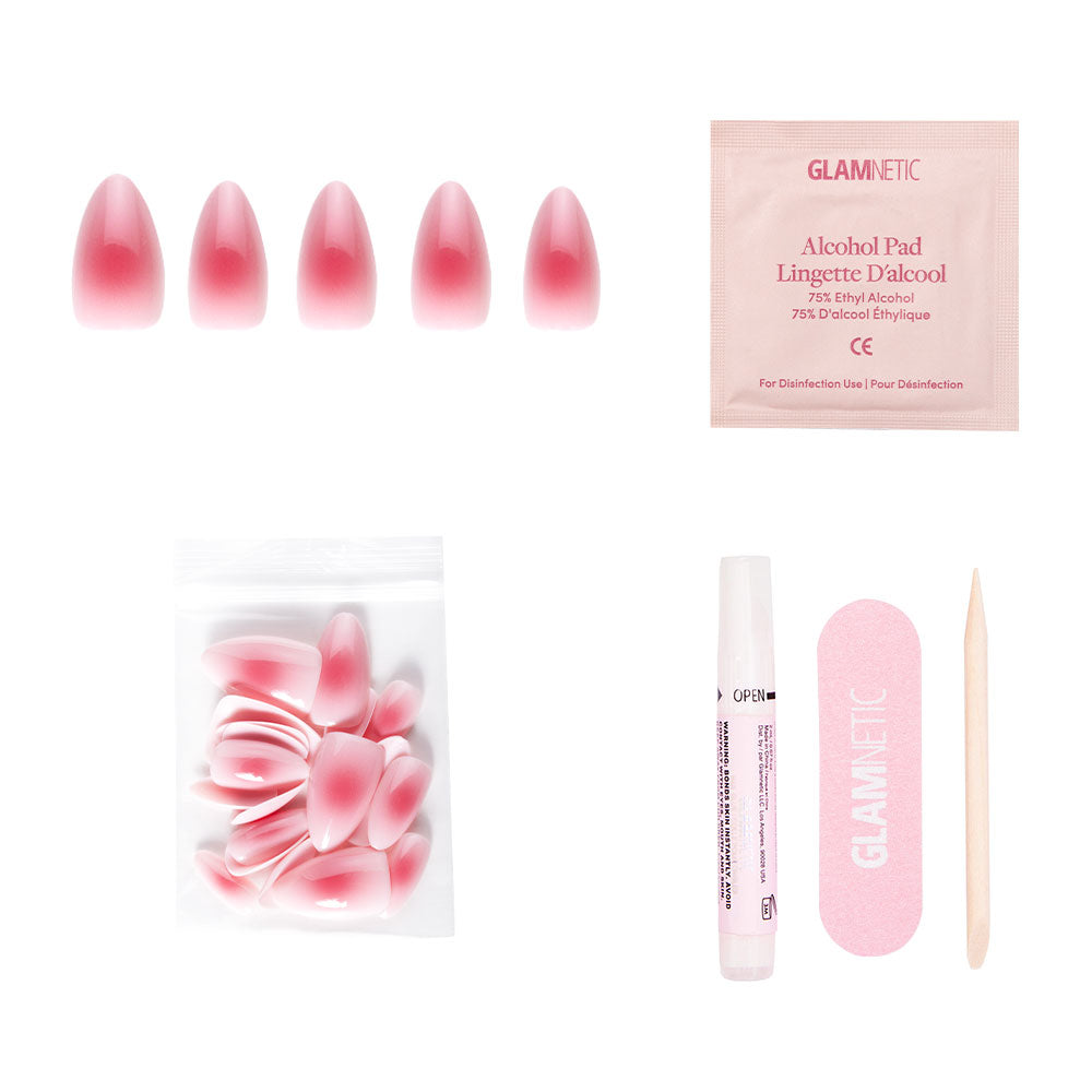 The glamnetic Blushing Aura nail set includes short almond ombre pink nails with an abstract dark pink center, plus extra nails, nail glue, a pink file, alcohol pad, and wooden cuticle stick on a white background. - Product image