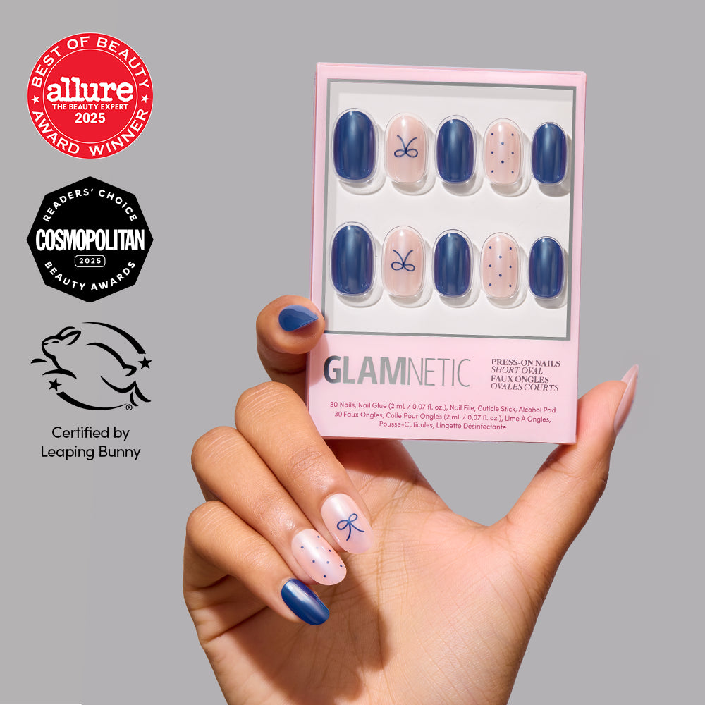 Bows & Bits - A hand holds a box of Glamnetic Bows & Bits short round press-on nails featuring solid navy blue, light pink with navy bows, and light pink with navy polka dots, with award icons displayed on the left.