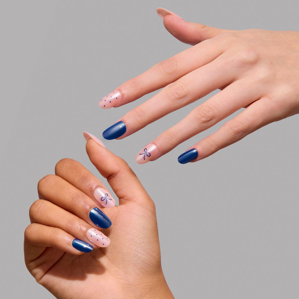 Bows & Bits - Two hands display Glamnetic Bows & Bits press-on nails featuring short, round tips in alternating solid dark blue, light pink with blue polka dots, and light pink with blue bow accents.