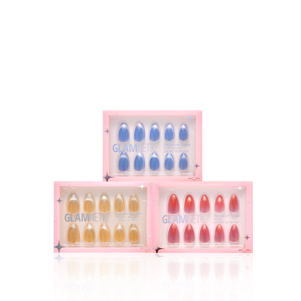 Three boxes of glamnetic Velvet Haze press-on nails are stacked pyramid-style. Each box displays vegan, cruelty-free short almond nails in blue, yellow, and pink shades within clear packaging edged in pink. - Product image