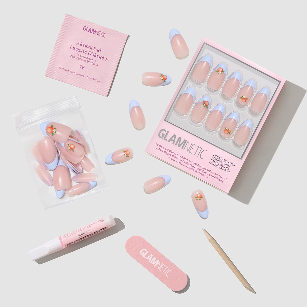 The glamnetic Capri Coast Press-On Nail Set features blue French tips, pink accents, and orange flowers. Get salon-quality nails at home with extra nails, a nail file, cuticle stick, alcohol pad, and adhesive—all on a light background. - Product image