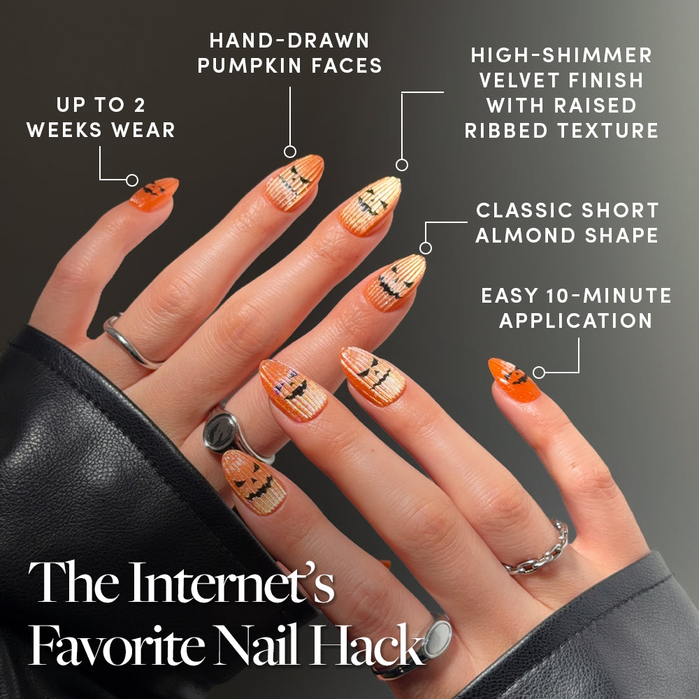 Close-up of hands wearing glamnetic’s Carving Contest short, almond-shaped press-on nails featuring an orange, shimmery, ribbed velvet finish and hand-drawn pumpkin nail art. Text highlights 2-week wear, easy application, and the unique velvet texture for a trendy look. Image reads: The Internet’s Favorite Nail Hack. - Product image