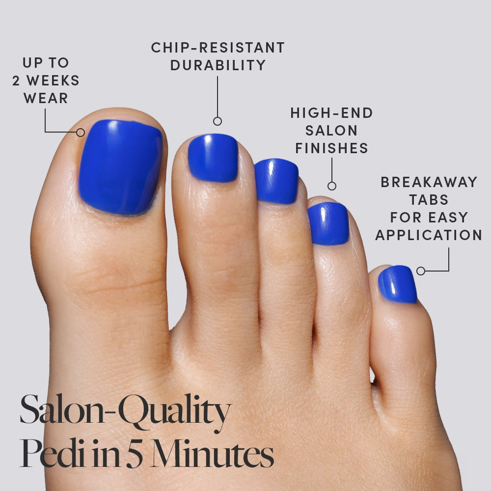 A close-up of blue Glamnetic press-on toenails on a foot, with icons describing their lasting and salon-quality perks. - Product image