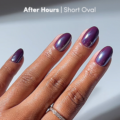 A hand with short oval nails from glamnetic, painted in the glossy, iridescent purple shade After Hours. The dazzling glazed finish enhances the look, complemented by a thin, diamond-studded ring on the person’s ring finger. - Product image