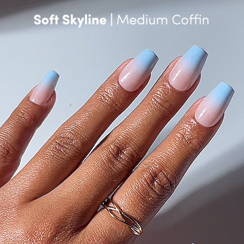 A hand showcases glamnetic’s Soft Skyline — a medium coffin nail set featuring a dreamy nude-to-blue ombré gradient. The elegant look is completed with a simple twisted ring on the finger. - Product image