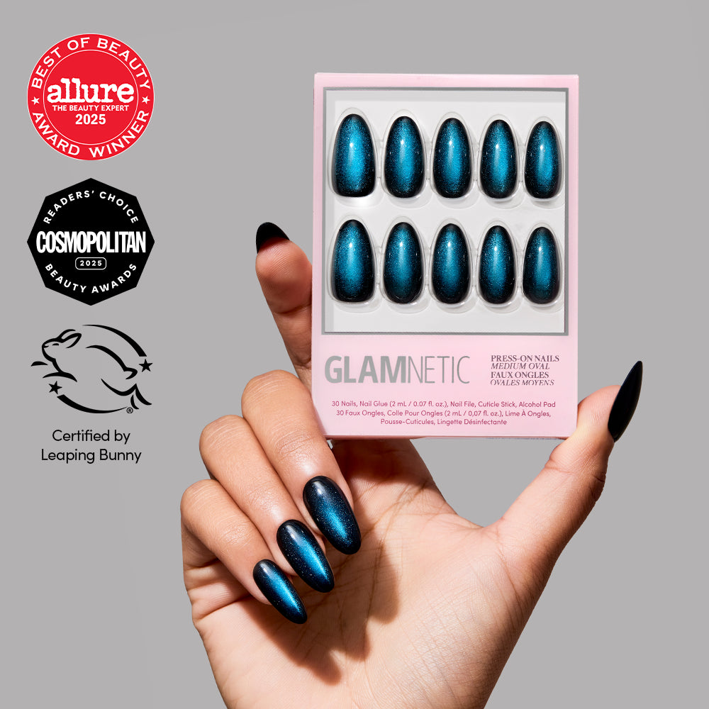 A hand with long, shiny, blue press-on nails holds a glamnetic Dark Waters nail set. Beauty award badges from Allure and Cosmopolitan, along with Leaping Bunny certification, are displayed on the left.