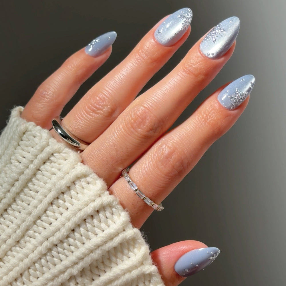 Glamnetic December Sky short almond nails in light blue with a velvet effect cat-eye shimmer and silver snowflake accents.
