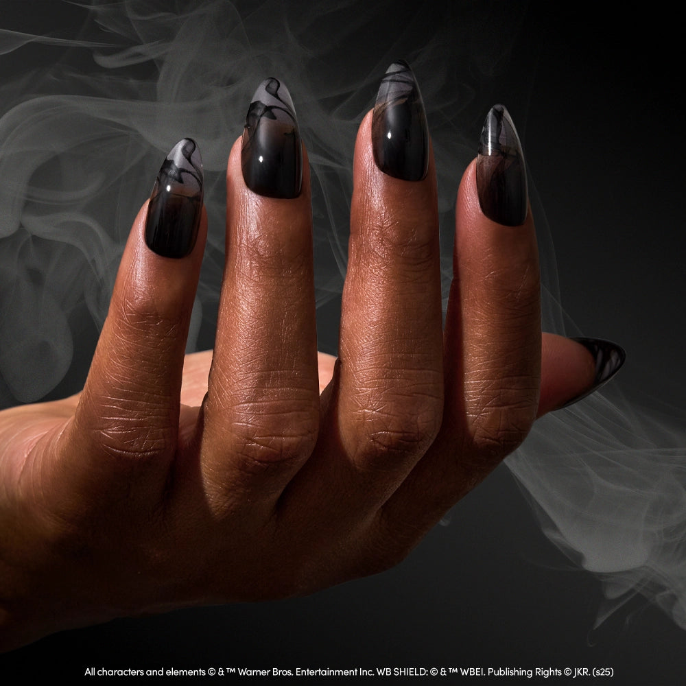 A hand with long, almond-shaped Dementor™ press-on nails by glamnetic, featuring smoky marbled designs, is held against a dark background with drifting wisps of smoke. - Product image