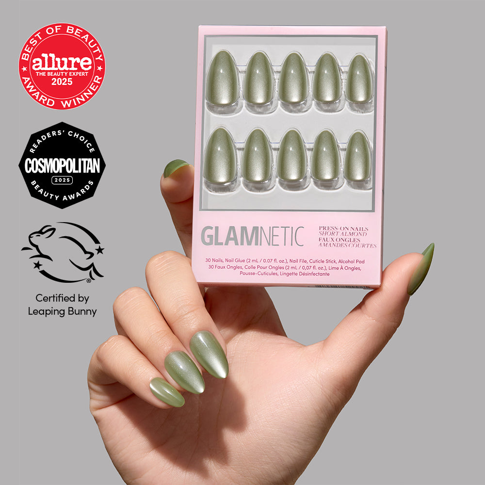 A hand holds a box of Glamnetic Dirty Martini press-on nails, showcasing the short, almond-shaped, velvet-finish nails with award seals from Allure, Cosmopolitan, and Leaping Bunny in the background. - Product image
