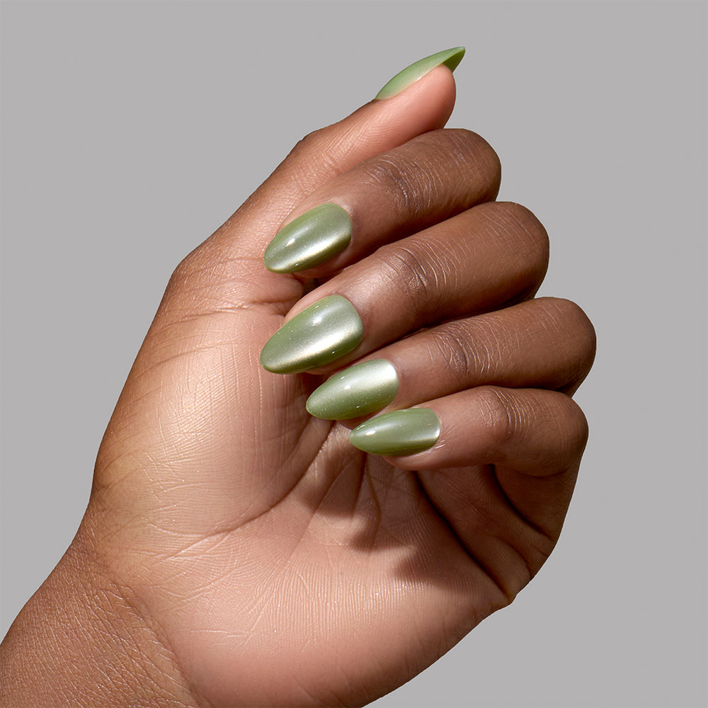 A hand with short almond Glamnetic Dirty Martini press-on nails in a shimmering olive green velvet finish. - Product image