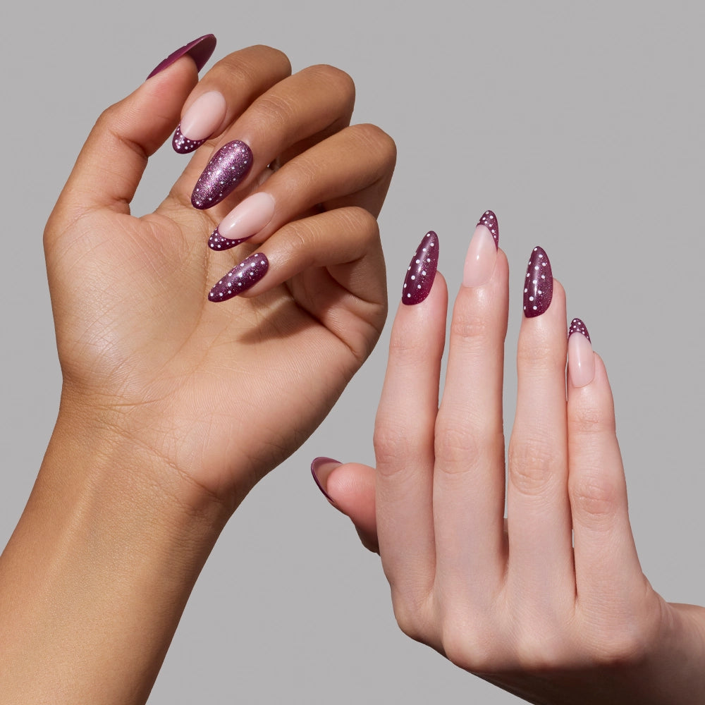 Two hands with long almond-shaped nails, styled with glamnetic’s Dotted Mulberry press-ons—featuring a burgundy and nude gradient embellished with playful white polka dots—are posed against a plain gray background. - Product image