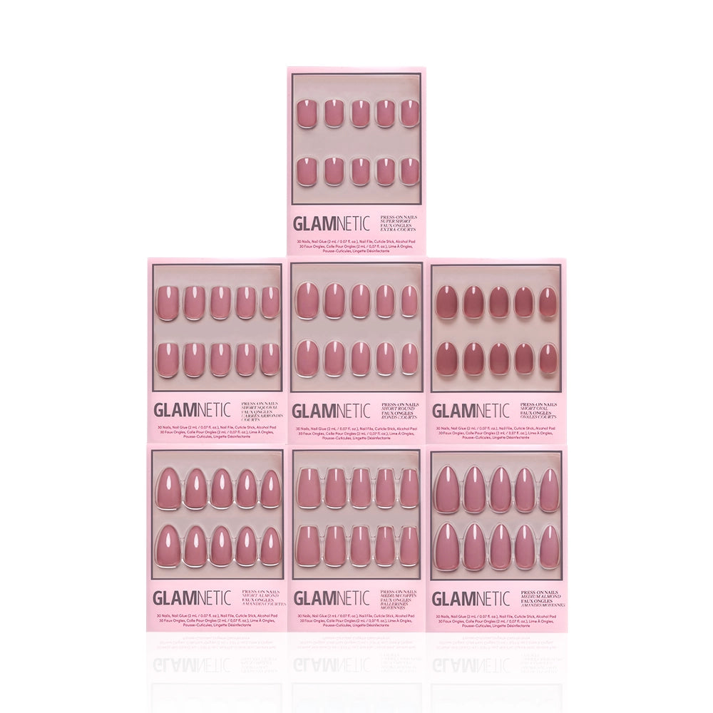 Seven boxes from the glamnetic Dreaming In Mauve Bundle, featuring various pink and mauve press-on nails in different shapes and lengths, are stacked in a pyramid against a white background—perfect for any nail style. - Product image