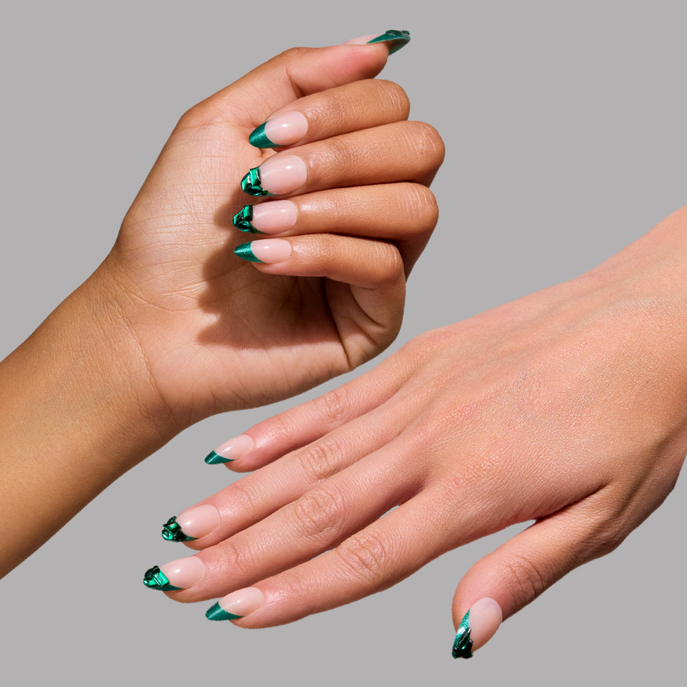 Two hands display glamnetic’s Emerald press-on nails—long, almond-shaped with a glossy nude base, metallic green French tips, and marble accents—set against a gray background for a salon-quality look.