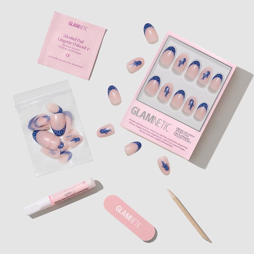 The glamnetic Whale Waves Press-On Nails set includes dark blue French tip designs, false nail glue, a pink nail file, wooden cuticle stick, alcohol pad, and extra nails—all displayed on a white background. - Product image