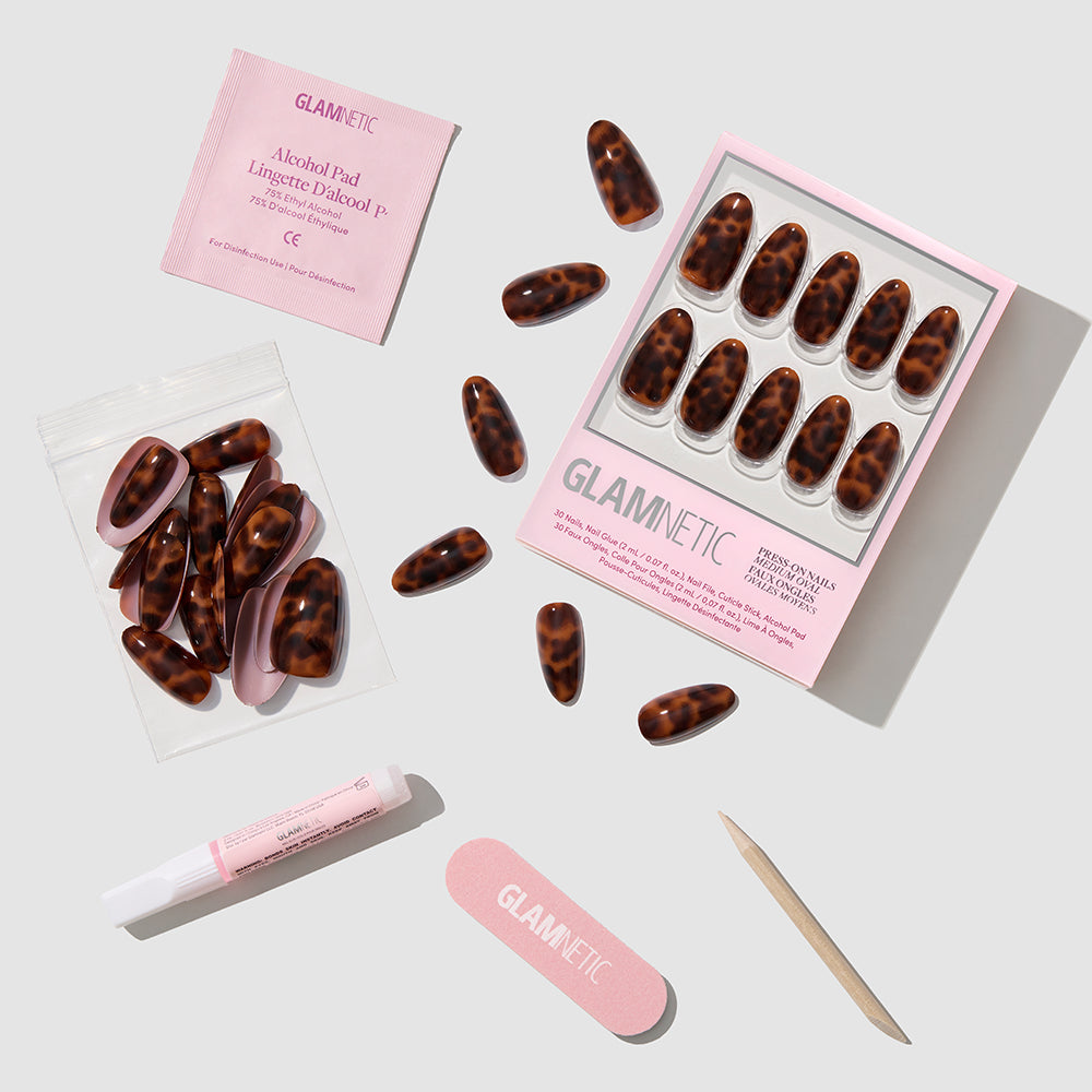 The glamnetic Expensive Taste press-on nails set features a brown tortoiseshell pattern, nail glue, pink file, wooden cuticle stick, alcohol pad, and extra nails for a salon-quality manicure—all shown on a white background. - Product image