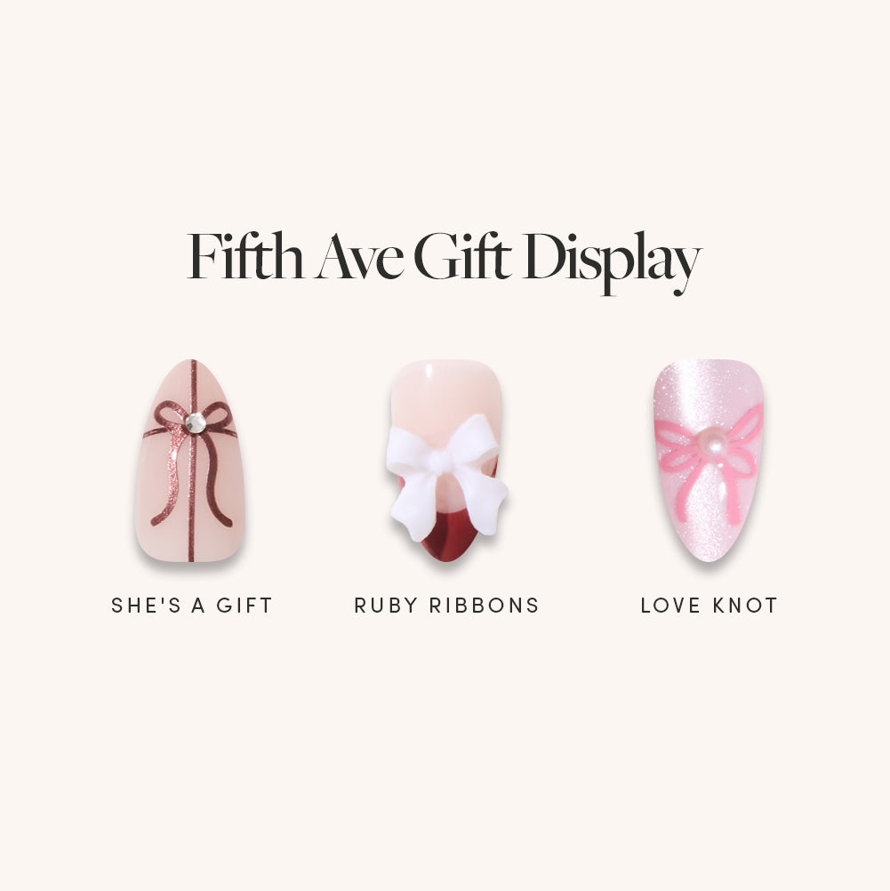 Elevate your holiday look with the glamnetic Fifth Ave Gift Display, a bundle featuring three press-on nails: She’s a Gift (brown bow with a gem), Ruby Ribbons (white bow over red), and Love Knot (pink ribbon knot on glitter). Each salon-quality set delivers festive flair in minutes—perfect for gift-inspired manicure lovers. - Product image