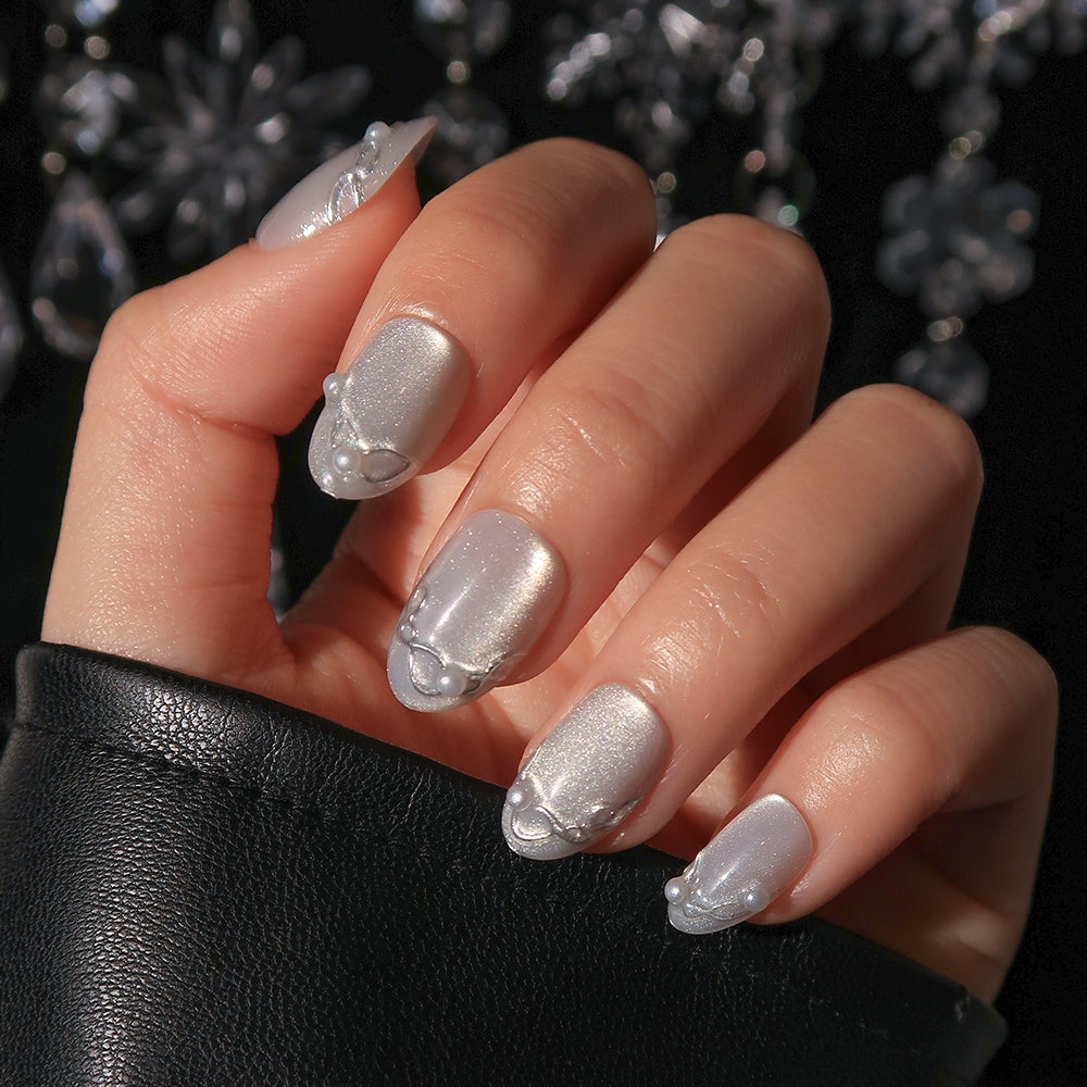 Glamnetic Fine Silver short, oval-shaped press-on nails featuring swirl accents and small white pearl embellishments. - Product image