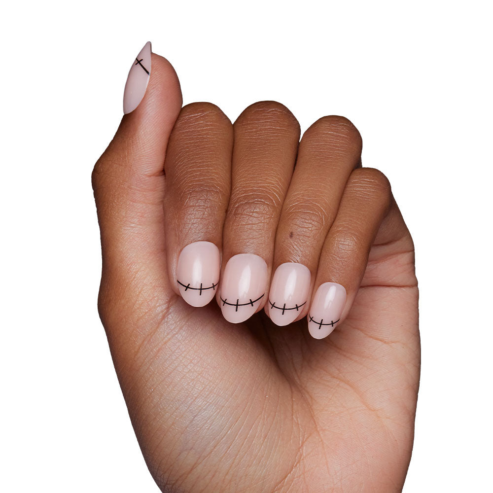 A hand with short oval nails painted light pink and accented with black stitch-like lines from the glamnetic Frankenbabe set, perfect for Halloween, shown against a white background. - Product image