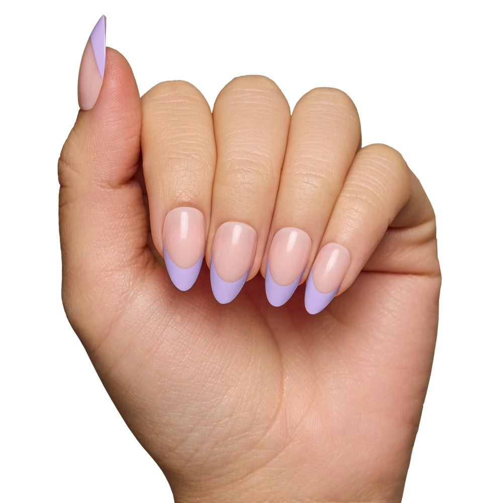 A hand with a manicure featuring glamnetic French Lilac Press-On Nails in a short almond shape, with a nude base and pastel purple tips, displayed against a white background. - Product image