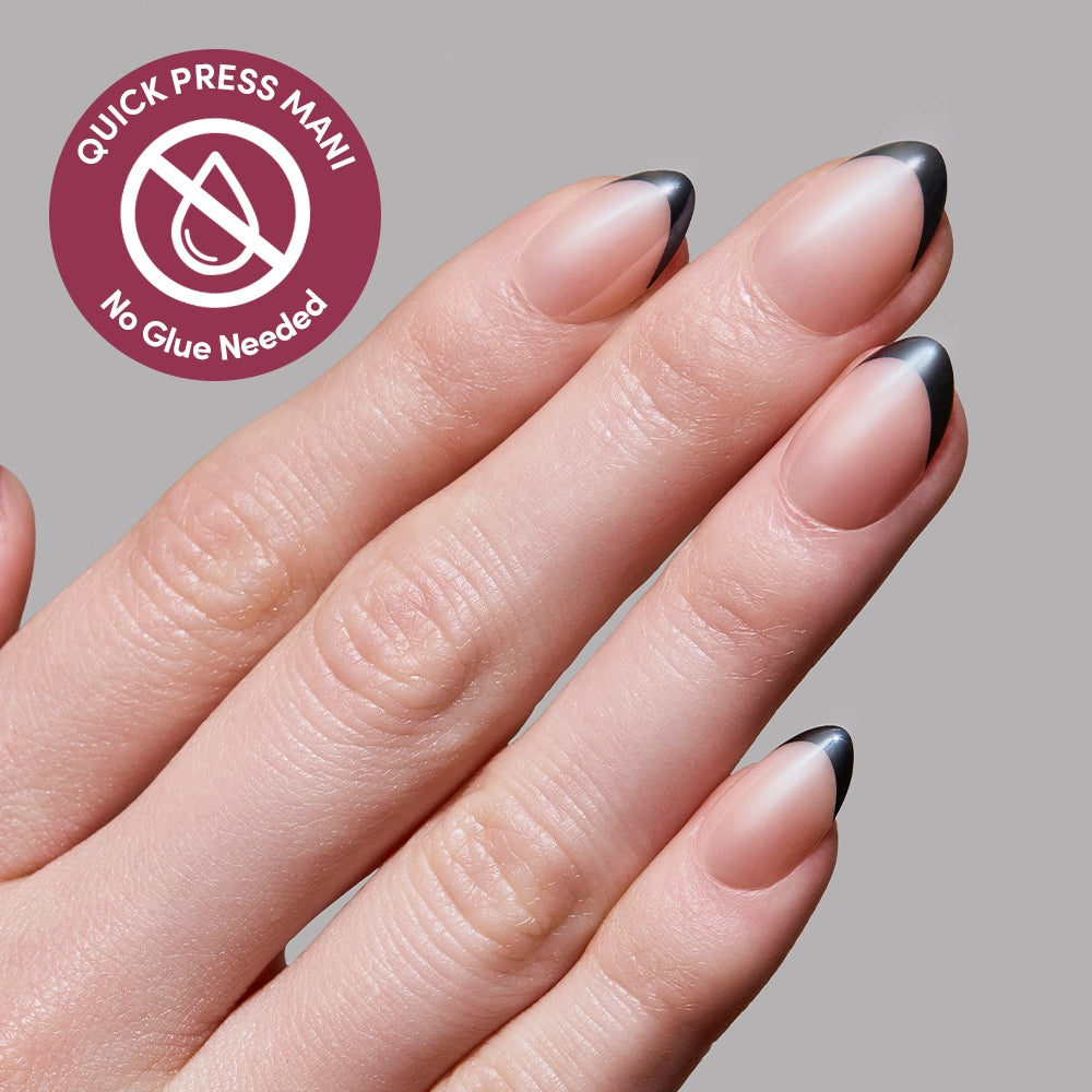 A hand displays glamnetic’s French Noir press-on nails—almond-shaped with a nude base and black French tips. A circular label says “Quick Press Mani - No Glue Needed.” The light gray background highlights these stylish nails. - Product image