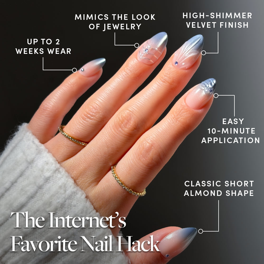 Frosted Crystals - A hand displays almond-shaped Frosted Crystals press-on nails with a blue-to-clear gradient and jewel accents, featuring a velvet finish, a two-week wear time, and easy application for a salon-quality manicure.