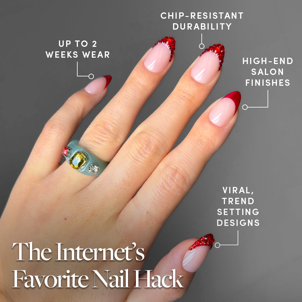 A hand with long, red Garnet French tips from glamnetic featuring glittery ends and adorned with a green gemstone ring. Text highlights these nails’ chip-resistant durability, up to 2 weeks of wear, high-end finishes, and trendy designs—perfect for fans of jewel-encrusted or garnet-inspired press-on nail looks. - Product image