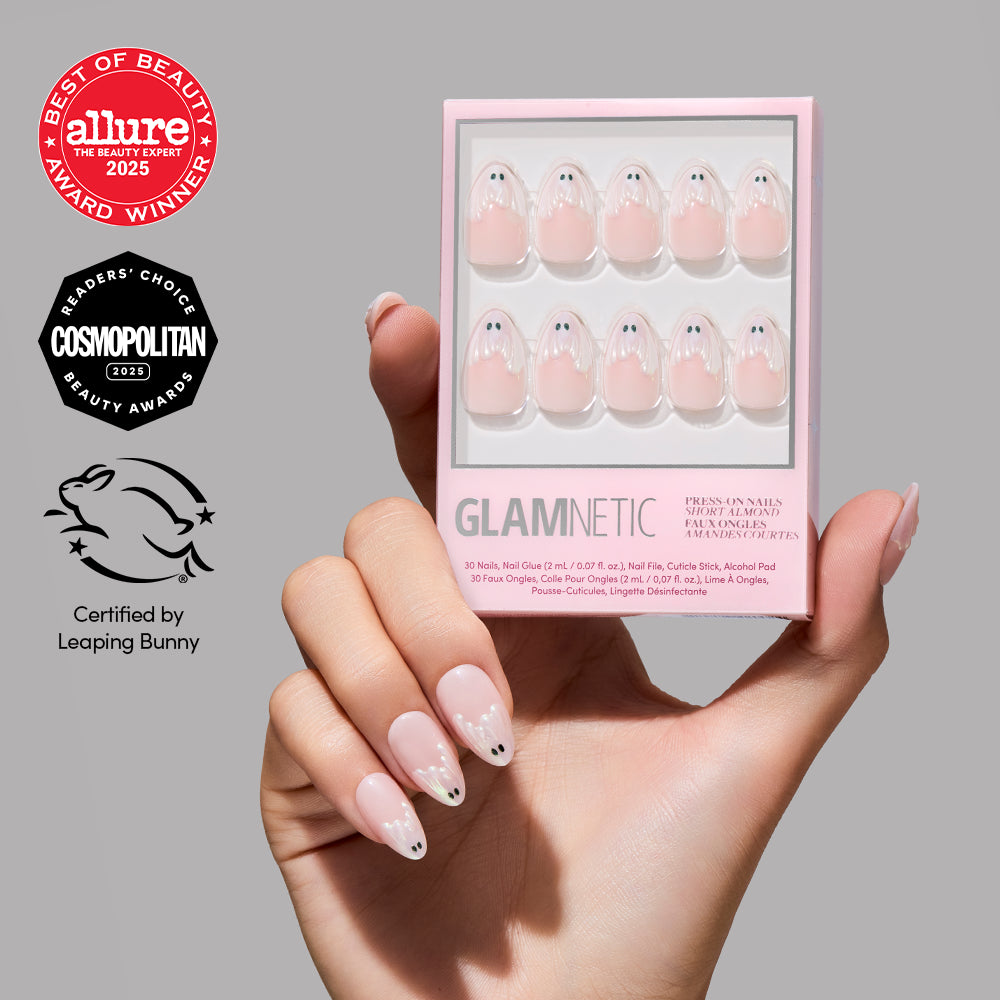 A hand with ghost-themed press-on nails in a short almond shape holds a Glamnetic nail kit, surrounded by beauty award logos and a Leaping Bunny cruelty-free certification. - Product image