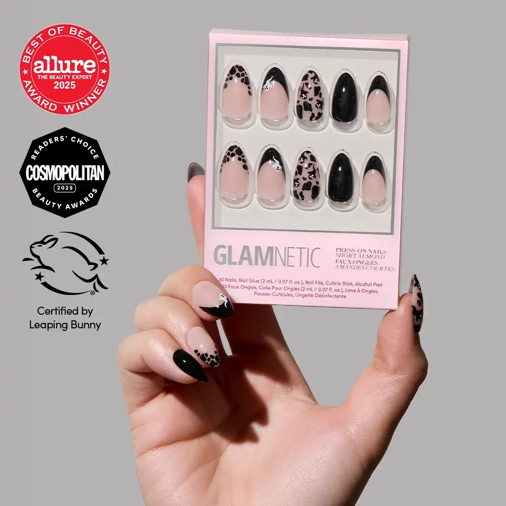 A hand with leopard print and black press-on nails holds a glamnetic Ghosted nail set, featuring short almond nails for a chic and modern look. Award badges for Allure 2025, Cosmopolitan 2023, and Leaping Bunny certification are visible on the left.