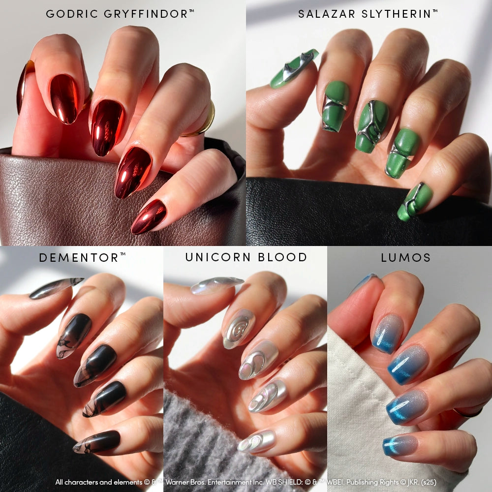 A hand displays Glamnetic House Faves press-on nails: chrome red (Gryffindor), green with silver (Slytherin), matte black (Dementor), shimmery white (Unicorn Blood), and iridescent blue (Lumos) by glamnetic.
