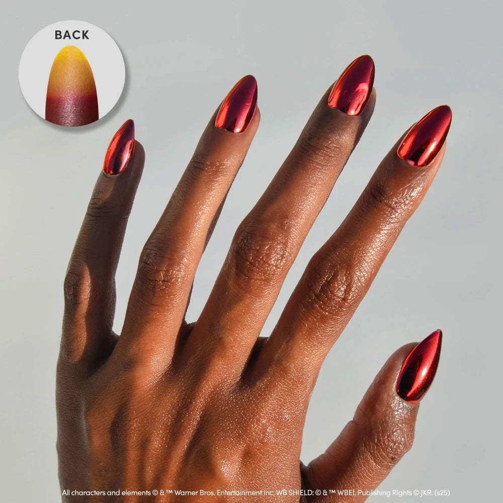 A hand displays long, almond-shaped, shiny red metallic nails from the glamnetic Godric Gryffindor™ set against a light background, perfectly showcasing the eye-catching effect of chrome almond nails. An inset features a close-up of a single nail viewed from behind, highlighting a bold gradient transition from red to yellow—evoking the striking style of the Godric Gryffindor™ collection by glamnetic.