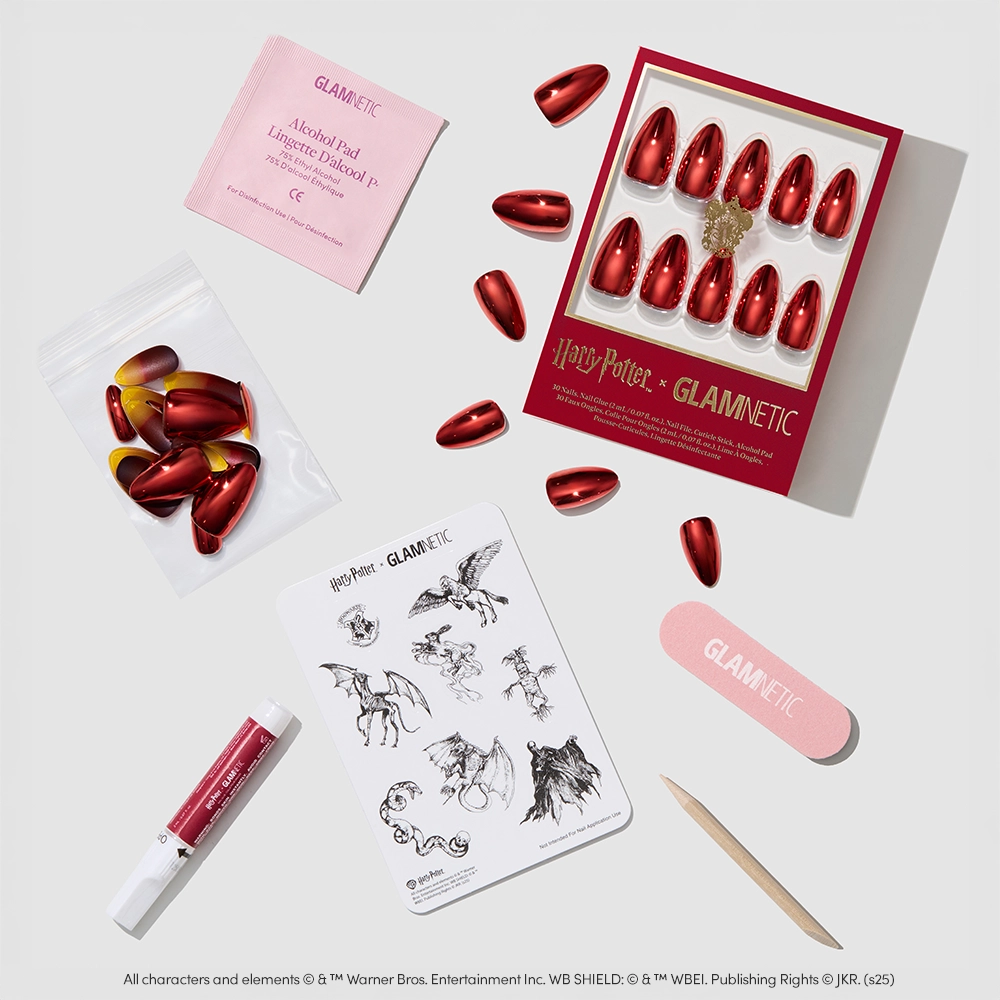 Flat lay of glamnetic's Godric Gryffindor™ set, showcasing red chrome nails, nail glue, alcohol pad, nail file, wooden cuticle stick, and Hogwarts-inspired temporary tattoo sheet. - Product image